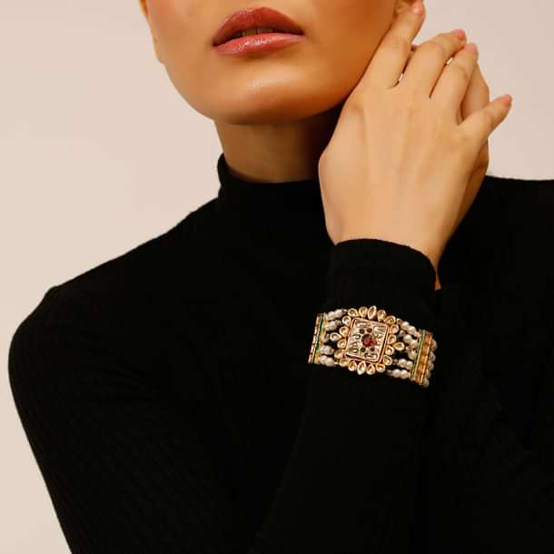 Gold Plated Bracelet With A Kundan Polki Centre Encrusted In A Red Stone And Multiple Moti Strings
